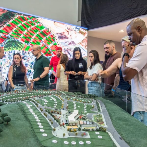 Foto de convidados observando a maquete do empreendimanto imobili«ario.